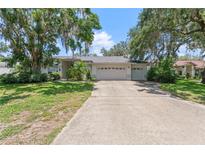 Charming single-story home featuring a two-car garage, mature trees, and a well-manicured front lawn at 1909 Masters Way, Plant City, FL 33566