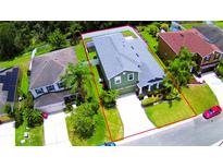 A beautiful green two-story home, surrounded by lush trees, manicured lawn, and a long concrete driveway at 2721 Walden Woods Dr, Plant City, FL 33566