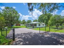 Scenic property featuring a gated driveway, lush greenery, and a cozy home perfect for outdoor enjoyment at 3611 Maxwell Rd, Plant City, FL 33566