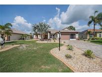 Charming single-story home featuring a well-manicured lawn, lush landscaping, and a paver driveway leading to a two-car garage at 2024 E Del Webb Blvd, Sun City Center, FL 33573