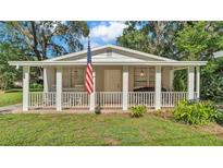 Charming home featuring a welcoming front porch adorned with an American flag at 4818 Huron St, Zephyrhills, FL 33541
