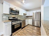 Updated kitchen with stainless steel appliances, granite counters, and modern white cabinets at 5980 80Th N St # 408, St Petersburg, FL 33709