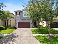 Charming two-story home featuring a paver driveway, manicured lawn, and mature trees at 1044 Oliveto Verdi Ct, Brandon, FL 33511