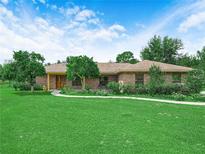 Charming brick home with manicured lawn, mature trees and a walkway leading to a wooden front door at 2815 Kebs Ln, Plant City, FL 33565