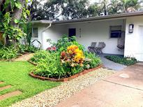 Charming home featuring a beautifully landscaped front yard with colorful plants and brick-lined garden beds at 4718 Crystal Ave, Sarasota, FL 34231