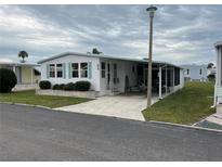 Mobile home with covered carport, landscaping, and screened porch at 626 Cervina Dr, Venice, FL 34285