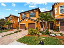 Orange two-story townhome with brown garage doors and landscaping at 20392 Lagente Cir, Venice, FL 34293