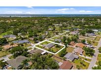 An aerial view of a quaint home with a large yard surrounded by lush greenery and other homes in a tranquil neighborhood at 566 Viridian St, Englewood, FL 34223