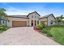Elegant stucco home featuring a paver driveway, tile roof, lush landscaping and a three-car garage at 284 Bocelli Dr., Nokomis, FL 34275