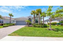 Charming one-story house with lush landscaping and a gray garage door at 15177 Spanish Point Dr, Port Charlotte, FL 33981