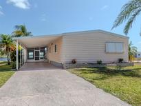 Peach-colored mobile home with carport and landscaped yard at 109 Lakeview Dr, North Port, FL 34287