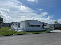 White single-wide manufactured home with carport and small deck at 923 Cortina Blvd, Venice, FL 34285