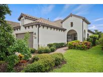 White two-story house with brown roof, landscaping, and a paved walkway at 11112 Mc Dermott Ct, Englewood, FL 34223