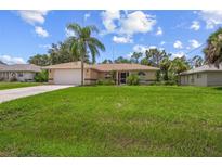 Tan house with a large yard and palm trees at 4619 Flint Dr, North Port, FL 34286