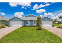 Two-unit building with light blue exterior, attached garages, and landscaping at 2129 Royal Tern Cir, Punta Gorda, FL 33983