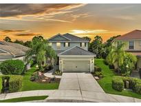 Two-story house with landscaped yard and attached garage at sunset at 12196 Alachua Ln, Venice, FL 34293