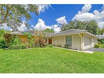 Tan house with a two-car garage and lush green lawn at 338 Pembroke Dr # 208, Venice, FL 34293