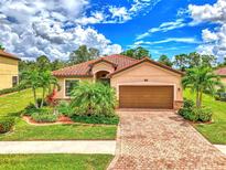 Single-story home with tile roof, landscaping and driveway at 12261 Canavese Ln, Venice, FL 34293