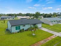Single-story home with a teal exterior and palm trees at 3704 Nekoosa St, North Port, FL 34287