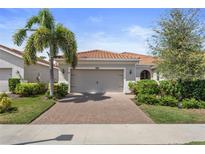 One-story house with tile roof, a two-car garage, and well-manicured landscaping at 12000 Tapestry Ln, Venice, FL 34293