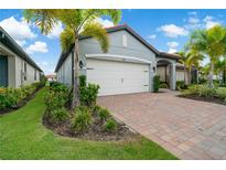 Single story house with white garage door, grey exterior, and landscaping at 240 Teramo Way, Nokomis, FL 34275