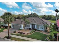 Inviting home featuring a barrel tile roof, lush landscaping, and a brick driveway at 594 Sawgrass Bridge Rd, Venice, FL 34292