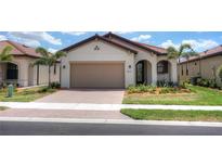 Single-story home with tan garage door and red tile roof at 24273 Spartina Dr, Venice, FL 34293