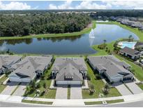 Stunning aerial view of homes backing to a lake with a fountain, pool, and lush landscaping at 12586 Oak Hill Way, Parrish, FL 34219