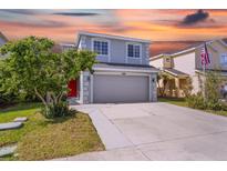 Two-story house with a gray exterior, red door, and two-car garage at 11898 Tempest Harbor Loop, Venice, FL 34292