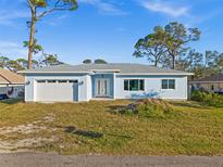 Newly constructed light blue home with a white garage door and landscaping at 1247 Graham Rd, Venice, FL 34293