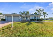 Single-story home with a white exterior, lush lawn, and palm trees at 1507 N Knollwood Dr, Bradenton, FL 34208