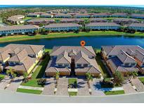 Stunning aerial view of a waterfront community featuring well-maintained townhomes, lush landscaping, and serene lake views at 20190 Ragazza Cir # 202, Venice, FL 34293