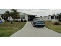 Charming single-story home with a well-maintained lawn, palm trees, and a concrete driveway at 6234 Parakeet Rd, Englewood, FL 34224