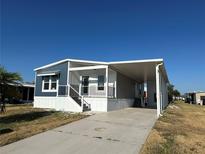 Charming manufactured home featuring a covered entrance, carport, and crisp blue and white paint at 127 Nautical Dr, North Port, FL 34287
