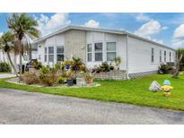 White single-wide manufactured home with landscaped yard and carport at 472 Sharks Pt, North Port, FL 34287