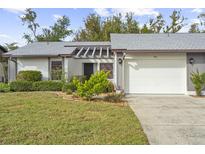 Charming condo with gray roof, white garage door, and well-manicured lawn at 605 Apple Ln, Englewood, FL 34223
