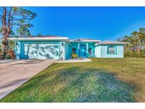 Light teal house with a two-car garage and nicely landscaped lawn at 13168 Peck Ave, Port Charlotte, FL 33953