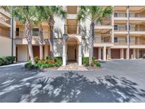 Elegant building entrance with palm trees and paved pathway at 830 The Esplanade N # 203, Venice, FL 34285