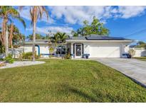 White house with solar panels, landscaped lawn, and palm trees at 1030 Phorus Rd Rd, Venice, FL 34293