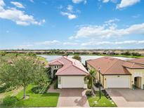 Beautiful home with red tile roof, brick driveway, and lake view from the well maintained lawn at 10637 Corkwood Ct, Venice, FL 34293