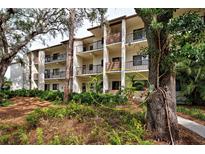 Condo building exterior with lush landscaping and walkway at 1174 Bird Bay Way # 107, Venice, FL 34285