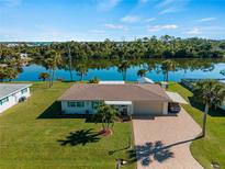 Single-story home with water view, large yard, and driveway at 1705 Meadowlark Ln, Englewood, FL 34224