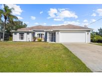 One-story home with a white exterior, attached garage, and well-maintained lawn at 4467 Cinderella Cir, North Port, FL 34286