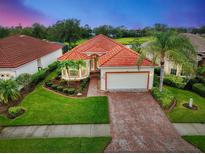 Single-story home with red tile roof, brick driveway, and landscaped yard at 5633 Whispering Oaks Dr, North Port, FL 34287