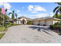 Beautiful single-story home featuring a three-car garage, brick paved driveway, and tropical landscaping at 793 Vanderbilt Dr, Nokomis, FL 34275