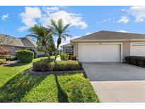 Exterior view of a light beige villa with a two-car garage, lush landscaping, and palm trees at 3897 Fairway Dr, North Port, FL 34287