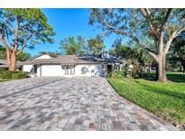 White two-car garage condo with paver driveway and mature landscaping at 4765 Oak Forest W Dr # 47, Sarasota, FL 34231