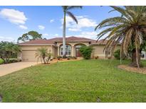 Single-story home with a red door, landscaping, and a large yard at 150 Marker Rd, Rotonda West, FL 33947