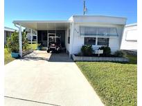 White mobile home with carport, golf cart, and landscaped yard at 218 Trailorama Dr, North Port, FL 34287