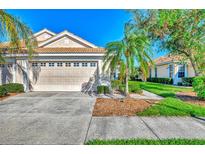 Two-car garage, mature landscaping, and a paved driveway at 4245 Whispering Oaks Dr, North Port, FL 34287